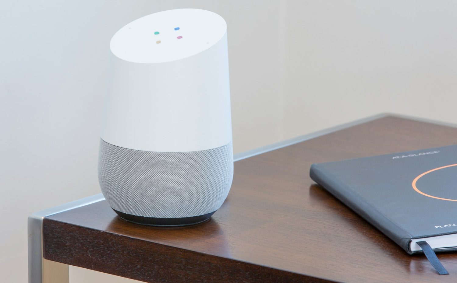 A smart speaker on a desk beside a laptop
