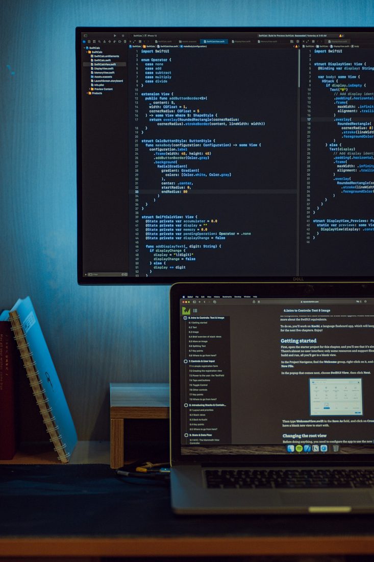 A developer working across two screens of application code