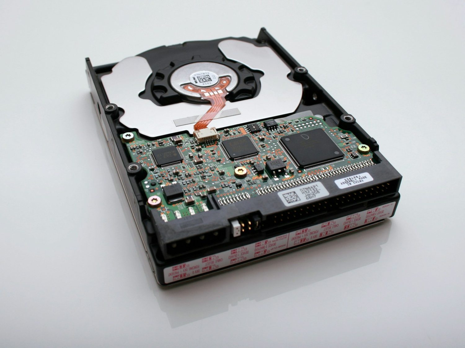 An opened hard drive showing its platter and circuit board