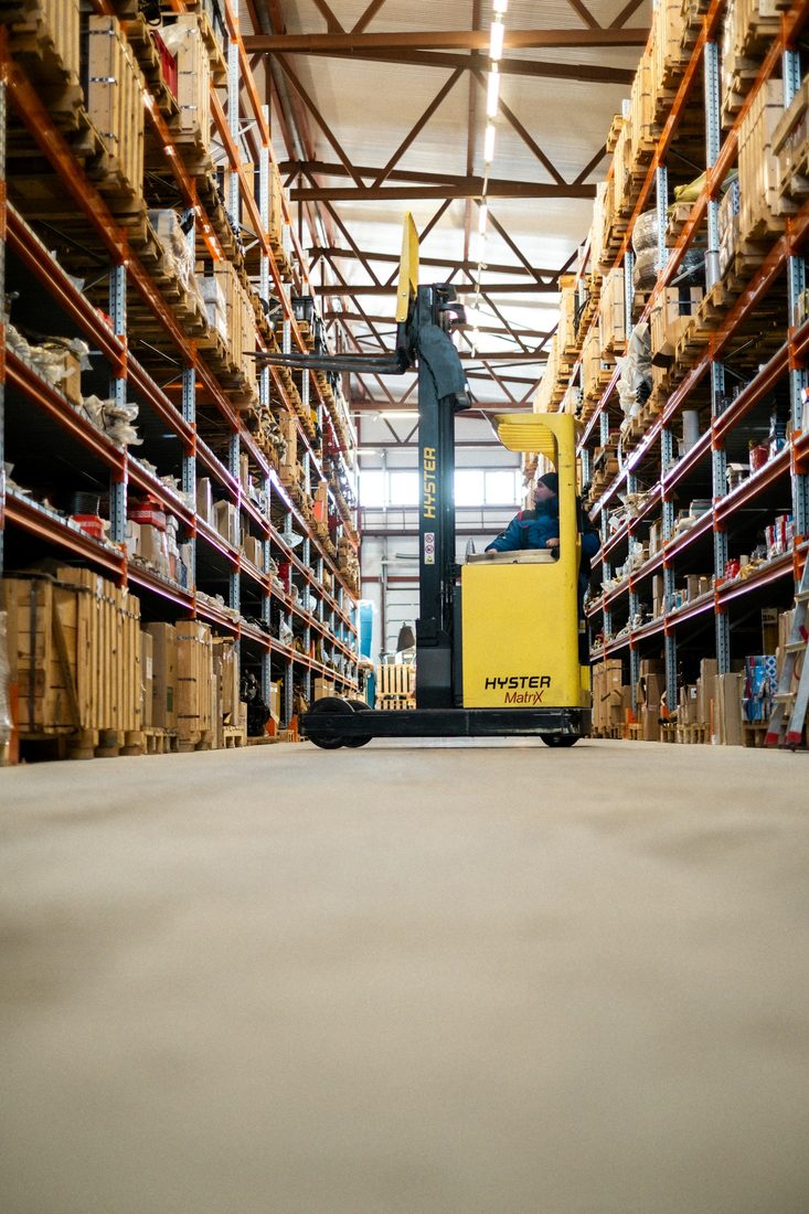A forklift moving stock down a warehouse aisle
